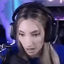 a woman wearing headphones is making a funny face while playing a video game .