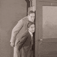 two men standing next to each other in front of a door with the number 1 on it