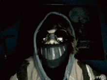 a person wearing a gas mask and a hooded jacket is standing in the dark .