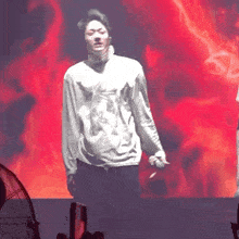a man is standing on a stage holding a microphone and smoking a cigarette .