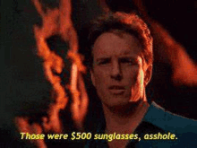 a man is standing in front of a fire and says those were $ 500 sunglasses asshole .