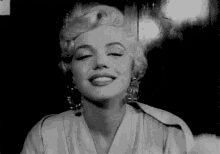 a black and white photo of marilyn monroe smiling with her eyes closed