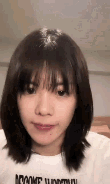 a close up of a woman 's face with short hair and bangs wearing a white shirt .