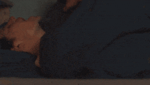 a young man in a green shirt is laying in bed with his eyes closed