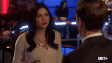 a woman in a white shirt is talking to a man in a black suit .
