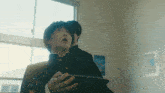 a boy in a school uniform is holding a book and looking up