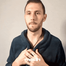 a man with a beard is wearing a blue sweater with the word mcdh on the bottom