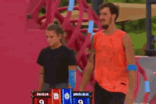 a man and a woman are standing next to a scoreboard with the number 9 on it .