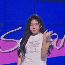 a young woman wearing a white t-shirt and a headband is waving at the camera .