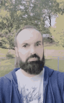 a man with a beard wears a blue hoodie