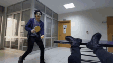 a man is playing ping pong in a hallway next to a ping pong table that says metropol