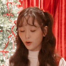 a close up of a girl 's face with a christmas tree in the background