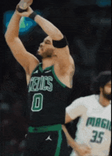 a basketball player wearing a celtics jersey reaches up to catch a ball