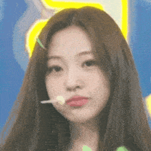 a close up of a woman with long hair holding a lollipop in her mouth .