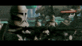 a group of clone troopers are holding guns in front of a at at walker