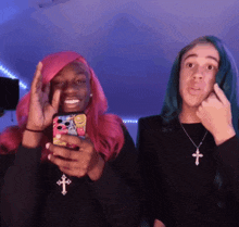 a girl with pink hair is holding a phone next to a boy with blue hair