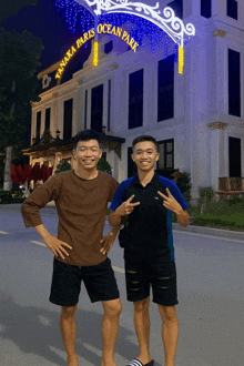 two young men are posing in front of a building that says ocean park
