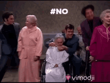 a group of people are standing around an elderly woman in a wheelchair with #no written on the screen