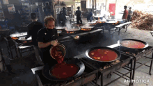 a man pours a bucket of sauce into a large pot