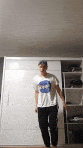 a man wearing a nasa shirt is standing in front of a white closet