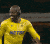 a soccer player wearing a yellow netbet jersey