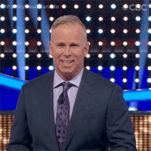 a man in a suit and tie is smiling in front of a wall of lights .