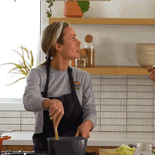 a woman in an apron is stirring a pot