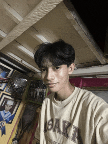 a young man wearing a osaka t-shirt takes a selfie
