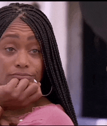 a woman with braids and hoop earrings is covering her mouth with her hand