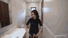 a woman in a black shirt is standing in a bathroom next to a toilet .