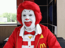 a mcdonald 's clown is wearing a red jacket with a m on it