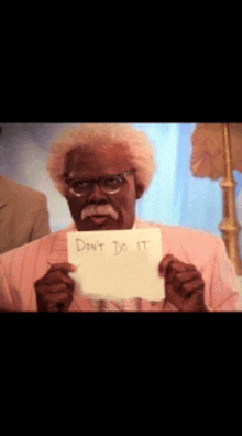 a man with glasses and a mustache is holding a piece of paper that says " don 't do it "