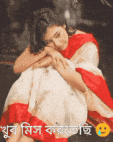 a woman in a red and white dress sits with her head on her lap
