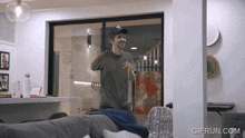 a man standing in a living room with a gifrun.com logo