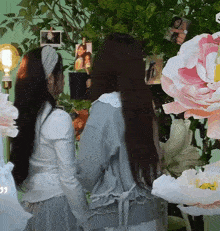 two women are standing next to each other in front of flowers and pictures