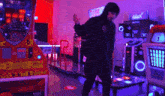 a man in a hoodie is dancing in an arcade with a machine that says ' sonic ' on it