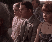 a group of people are sitting in a row and one of them is wearing a necklace
