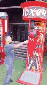a man is playing a boxing game in front of a red boxen machine