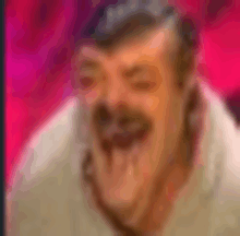 a blurry picture of a man with a mustache laughing with his hand on his face .