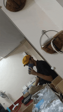 a man in a yellow hat takes a picture of himself in the mirror