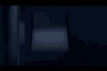 a person is standing in a dark room with a light shining through the window .