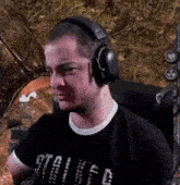 a man wearing headphones and a black shirt is sitting in a chair and making a funny face .