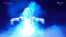 a man with dreadlocks is surrounded by blue smoke and a fox live logo