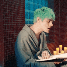 a man with green hair is sitting in a bathrobe reading a book .