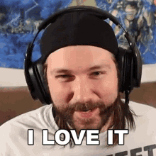 a man with a beard is wearing headphones and a beanie and says `` i love it '' .