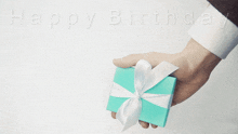 a man is holding a blue gift box with a white bow and the words happy birthday written above him