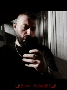 a man with a beard is taking a selfie with his phone in a dark room .