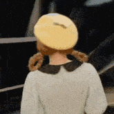 a woman wearing a yellow beret and a white dress is standing in front of a black background .