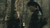 a man and a woman are standing next to each other in a dark forest