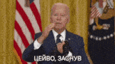 a man in a suit and tie is giving a speech in front of two microphones in front of an american flag .